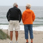 An elderly couple looking out over the ocean at the beach