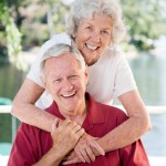 A married couple in their eighties show affection on their outdoor deck.